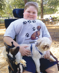 Jared Watson, prior to his spinal surgery, wearing a back brace and holding his dog, Gizmo.