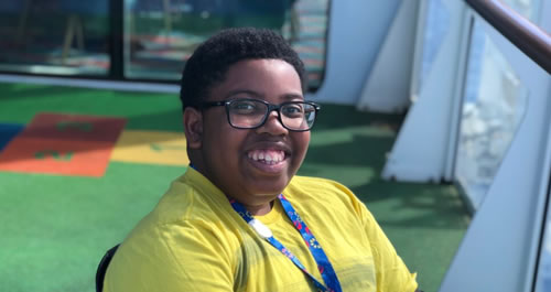 A young boy with glasses and a yellow shirt sitting down