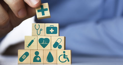Fingers holding child building blocks with medical icons on them