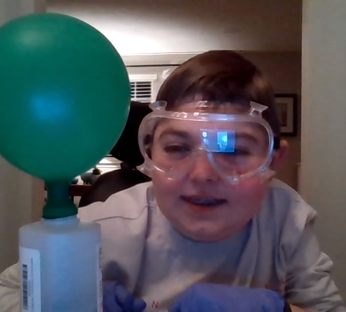 Boy with safety glasses and gloves creating a science project.