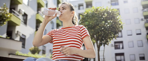 Woman in wheelchair drinking a bottle of water.