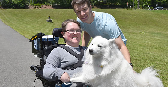 A picture a boy in a wheelchair with a friend and a dog.