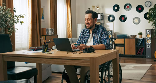 Man in wheelchair at desk in front of a laptop