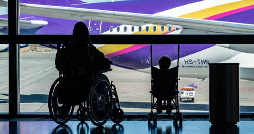 An adult and child in wheechairs sitting in the airport