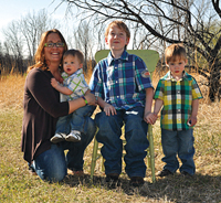 Payton Mueller (seated) at age 11, with growing rods in place. Payton’s mother, Rachele Krebsbach, is holding Payton’s 1-year-old brother Korbyn Krebsbach, and 3-year-old brother Ryker Krebsbach is standing next to Payton.