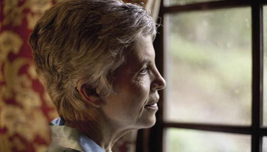 An elderly woman staring out of a window