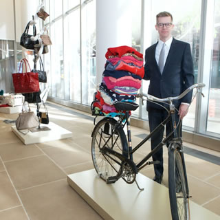 A man in a suit standing by a bike, at WOWs 2019.