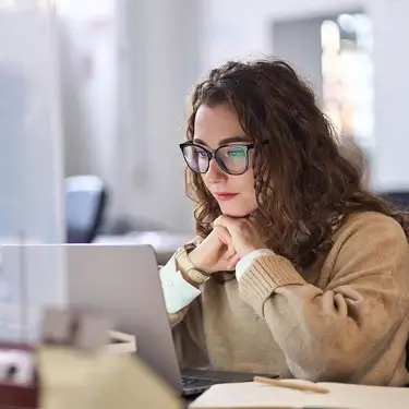 A photo of a person in front of a laptop.