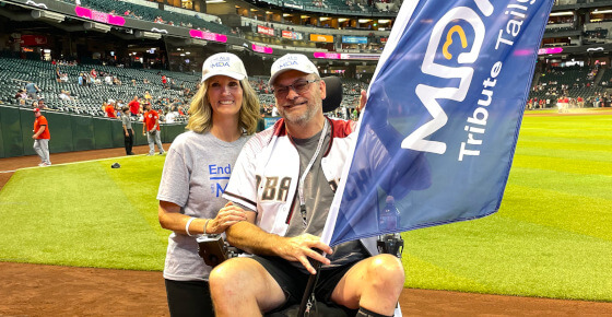 A picture of a man and a woman with End ALS baseball caps at a ball game.