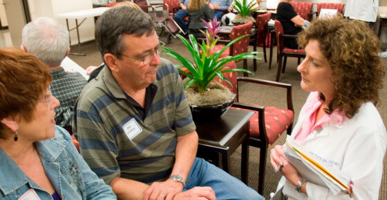 A photo of two people at a doctor's office consulting with someone in a white lab coat.