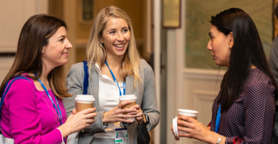 A photo of three women at the MDA conference talking and drinking coffee.