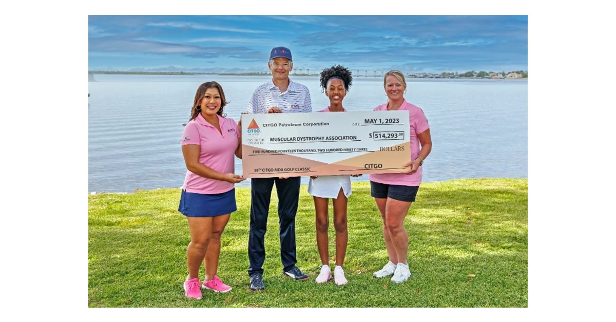 Four people standing in fromt of a big checkon the grass in front of a lake.