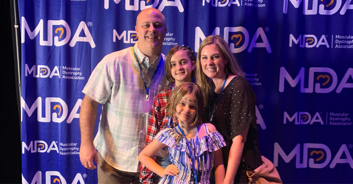 Image of a family in front of an MDAwall banner.