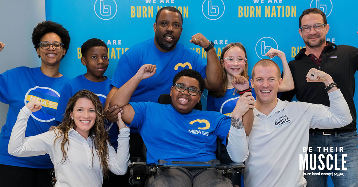 A group of people posing with their arms flexed in front of a Burn Boot Camp banner.