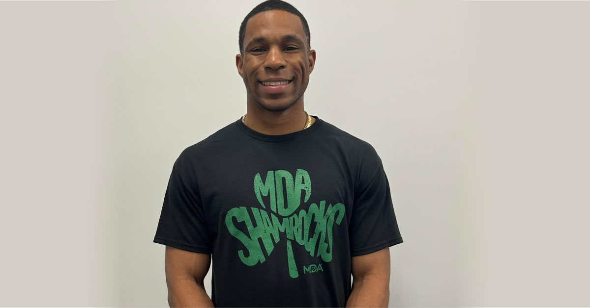 A man smiling while wearing a MDA Shamrocks tshirt