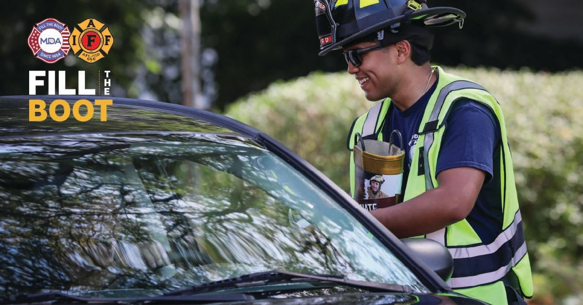 Image of a Firefighter holding a boot and talking to someone in a car.