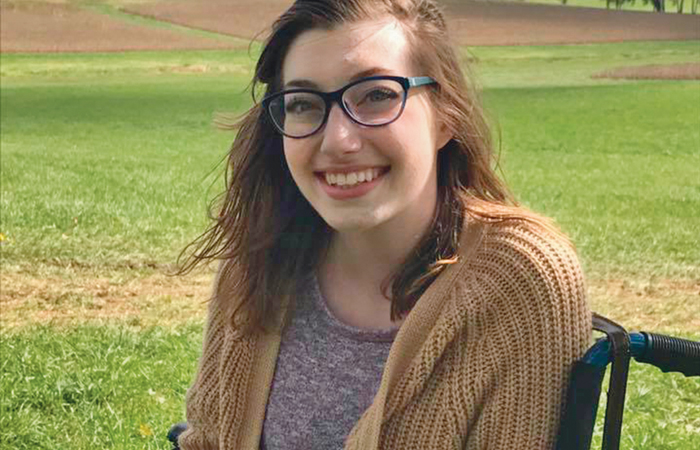 A picture of Rene Runions smiling, sitting in a field of grass